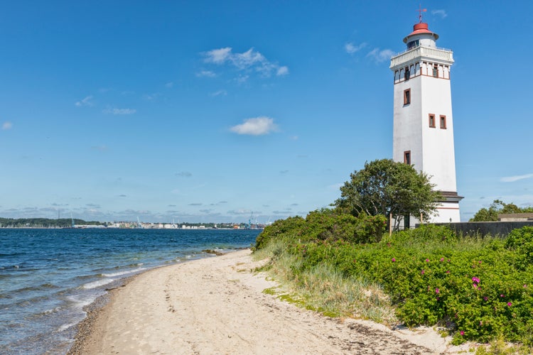 photo of view of Lighthouse at the beach of Strib, Middelfart, Denmark. harbor of Fredericia in background, Middelfart, Denmark.