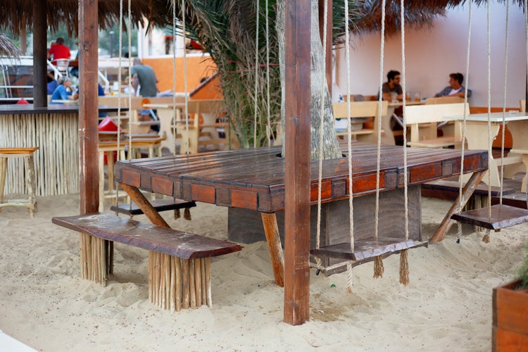 Beautiful wooden picnic table and benches on sandy beach .