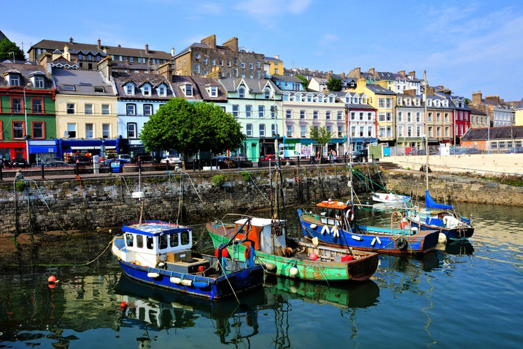 Photo of Old boats with colorful harbor buildings in background in the port town of Cobh, County Cork, Ireland.