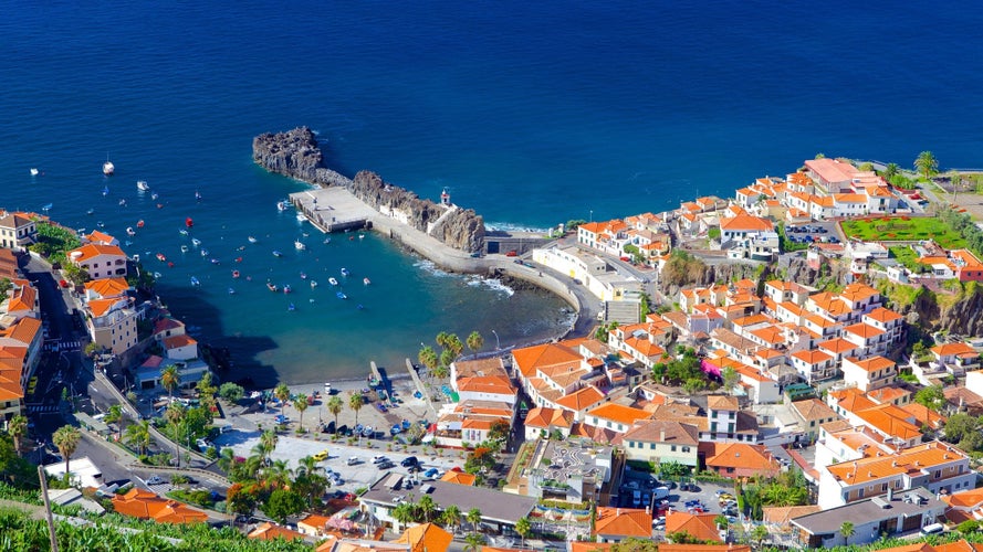 Amazing Madeira island with beautiful fishing Câmara de Lobos village with houses, pier, mountain and ocean