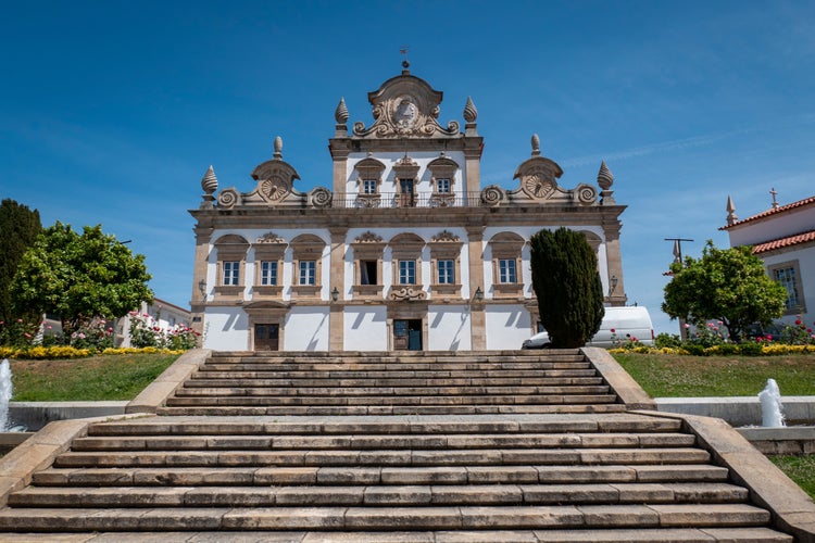 Photo of Mirandela City Hall building and the access stairs to it, surrounded by a beautiful garden and a blue sky in Trás os Montes, Portugal.