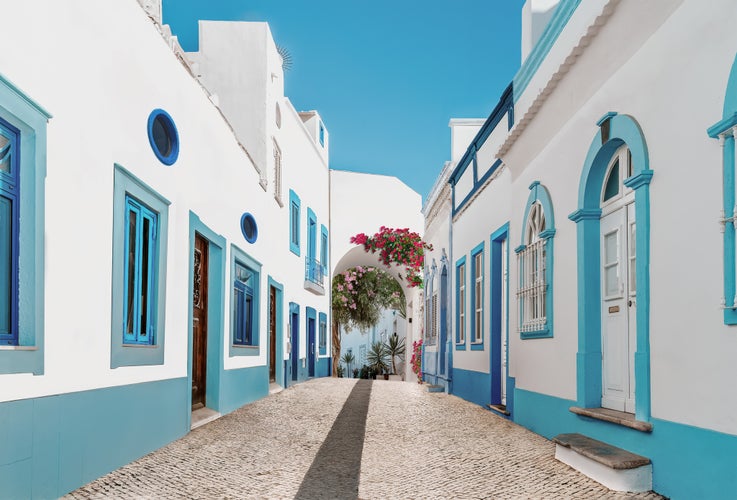 Photo of Street in fishermen village with white and blue houses and typical Portuguese pavement in Olhao, Algarve region - Popular travel destinations in Portugal.