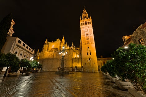 Photo of Seville Cathedral with Giralda Bell Tower, a former Moorish mosque , Spain .