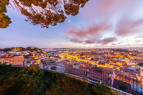 Photo of city view of Lisbon after sunset from Belvedere of Our Lady of the Mount or Miradouro da Nossa Senhora do Monte, Portugal.