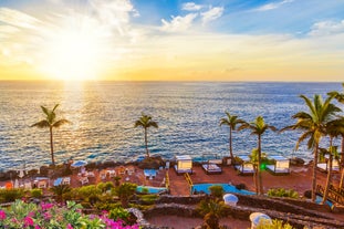 photo of aerial shot of Costa Adeje area, South Tenerife, Spain. Captured at golden hour, warm and vivid sunset colors. Luxury hotels, villas and restaurants behind the beach.