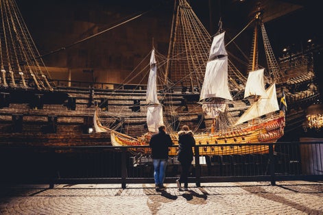 People in front of model of Vasa, viking ship. The ship itself in the background