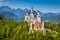 Photo of aerial beautiful view of world-famous Neuschwanstein Castle, the 19th century Romanesque Revival palace built for King Ludwig II, with scenic mountain landscape near Fussen, southwest Bavaria, Germany.