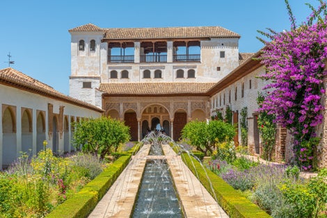 Photo of the Generalife courtyard, with its famous fountain and garden through an arch. Alhambra de Granada complex at Granada, Spain.