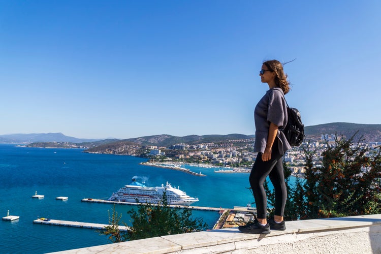 Kusadasi, Turkey, A young girl is looking to the sea, Kusadasi skyline and luxury cruise ship in the background.