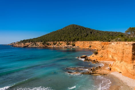 photo of "Es Bol Nou" is one of the natural beaches of the island of Ibiza, Spain. Surrounded by limestone cliffs that give it an orange color. It is a typical beach among the locals.