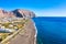 Photo of aerial view of black Perissa beach with beautiful turquoise water, sea waves and straw umbrellas, Greece.