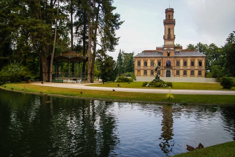 Photo of house with a turret and its reflection in the lake, Tarbes, France.