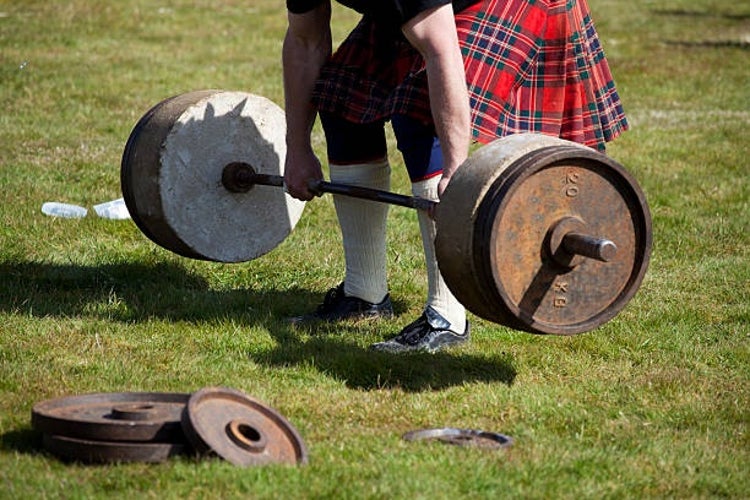 A Scotsman in traditional kilt lifting the -Stones of Density- during a strongman challenge at a Scottish Highland Games event.jpg