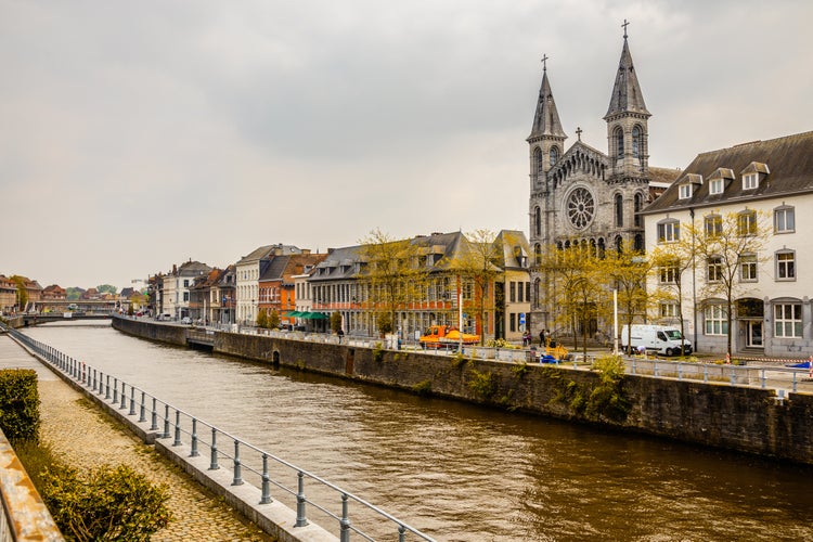 Photo of Escaut river and street with old belgian houses and facade of church of the Redemptorists of Tournai, Walloon municipality, Belgium.