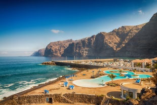 photo of aerial shot of Costa Adeje area, South Tenerife, Spain. Captured at golden hour, warm and vivid sunset colors. Luxury hotels, villas and restaurants behind the beach.