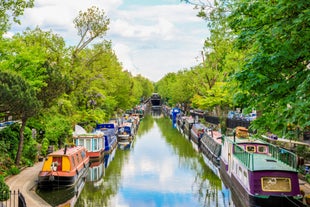 Photo of a narrow boat moored at the river Gade, Grand Union Canal. The Grove Bridge aka Grove Ornamental Bridge No 164 is in the background, Cassiobury Park, Watford, England.