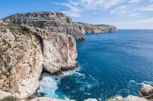 Photo of aerial view of seaside cliffs, colourful houses and streets of Qawra town in St. Paul's Bay area in the Northern Region, Malta.