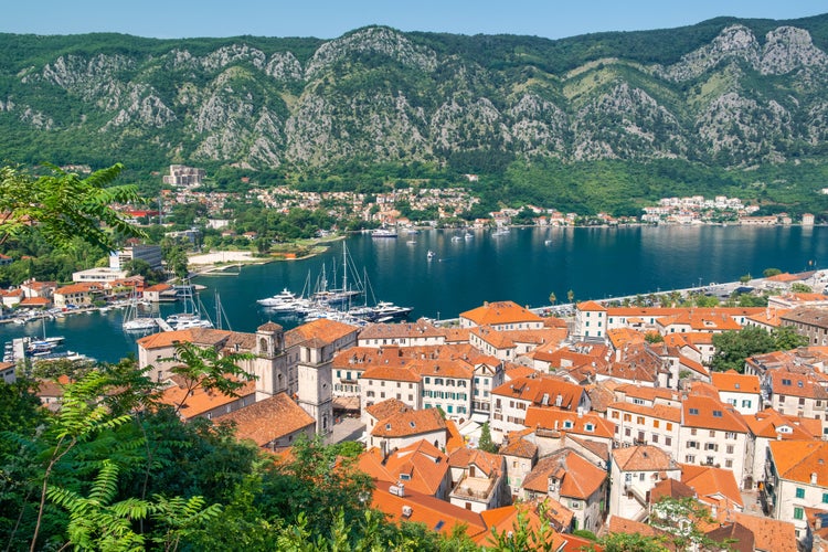 Photo of Aerial view of Kotor old town with orange rooftops and marina in Kotor bay with boats and yachts, Montenegro. Summer vacation resort on Adriatic fjord in summer day. Travel destination.