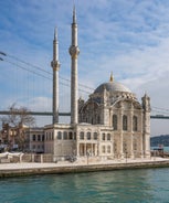 Touristic sightseeing ships in Golden Horn bay of Istanbul and mosque with Sultanahmet district against blue sky and clouds. Istanbul, Turkey during sunny summer day.