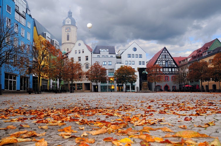 Photo of Historical buildings facing the market square, still empty in the foggy morning. There is a flying balloon catching a glimpse of sunshine. City of Jena, Thuringia, Germany.