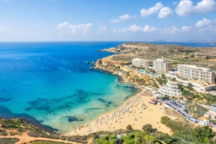 Photo of aerial view of seaside cliffs, colourful houses and streets of Qawra town in St. Paul's Bay area in the Northern Region, Malta.