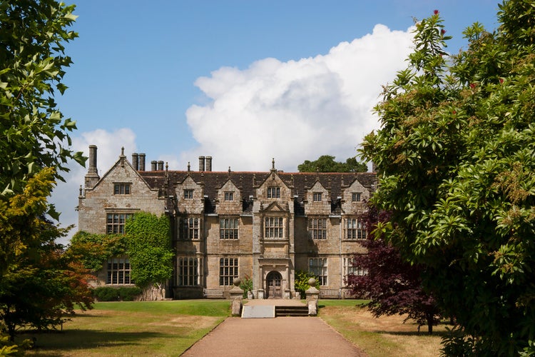 Photo of typically large English landscape garden with hedges, fences, plant and flower beds, lawn, pond and garden furniture, Chichester, England.