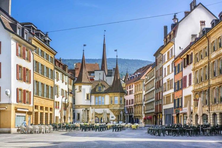  Neuchatel, Switzerland - Tourists enjoy outdoor dinning at Market place des Halles in front of La Maison des Halles building in Medieval ancient town of Neuchatel