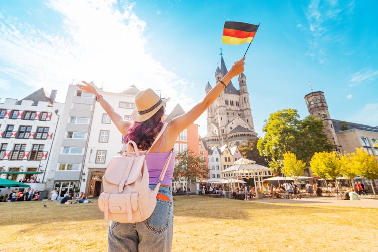 Photo of young happy tourist with a German flag at the old town or Altstadt in Cologne fish market square.