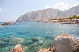 Photo of aerial view of black Perissa beach with beautiful turquoise water, sea waves and straw umbrellas, Greece.