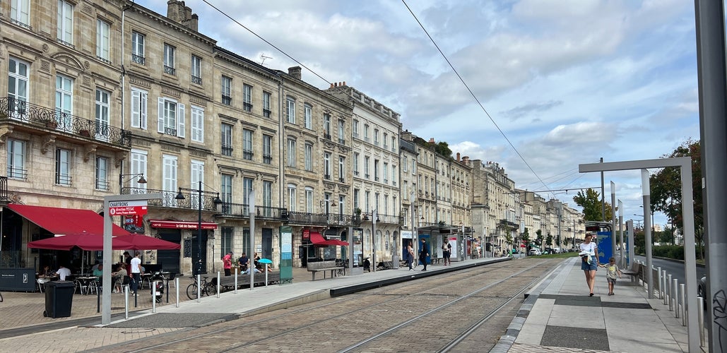 Chartrons tram station in Bordeaux with historic buildings, sidewalk cafés, and light foot traffic on a cloudy day..jpg