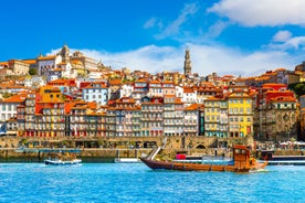 Photo of aerial view of Bilbao, Spain city downtown with a Nevion River, Zubizuri Bridge and promenade. Mountain at the background, with clear blue sky.